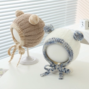 Detail of warm plush baby earflap hats with pom-poms and tie straps for winter