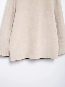 Gros plan sur l'ourlet et le détail de manche d'un manteau en fausse fourrure beige