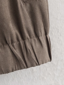 Detail of coffee brown suede jacket showing diagonal twill texture and precision stitching