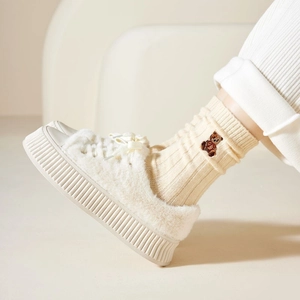 Close-up of beige thermal crew socks with cute bear embroidery and fuzzy shoes