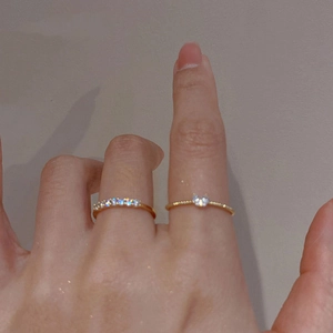 Minimalist gold heart ring set with zircons and cat motif on a light grey background