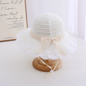 Detail of baby girl white lace straw hat featuring adjustable chin strap and bow