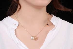 Detail of gold necklace with peace sign pendant and sparkling crystals on model