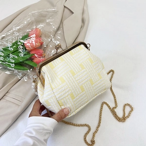 Close-up of woven yellow and white shell bag with gold clasp and chain strap