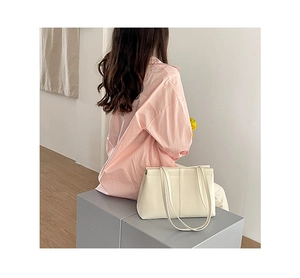 Minimalist beige shoulder tote bag with dual straps shown in a lifestyle setting
