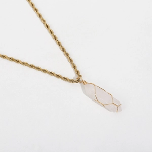 Macro detail of gold twist chain necklace with wire-wrapped pink crystal pendant