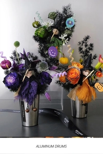 Detailed view of Halloween floral arrangements in silver tins with witch and pumpkin decor