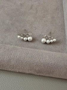 Detail view of silver pearl and zircon stud earrings on gray velvet tray display