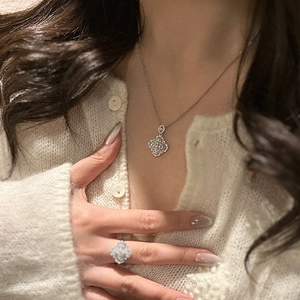 Detail of silver clover necklace and ring set with zircon on female model