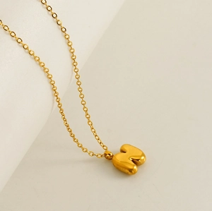 Detailed shot of gold-plated bubble letter M pendant on a delicate chain necklace
