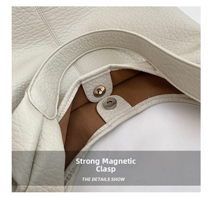 Detail view of the strong magnetic buckle closure on a beige lychee grain leather tote bag