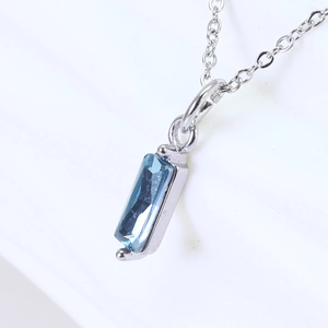 Close-up of a blue rectangular zirconia pendant on a polished silver chain necklace