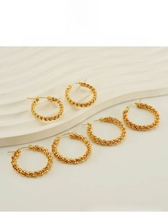 Detailed view of three pairs of gold-plated twisted rope hoop earrings on a white tray