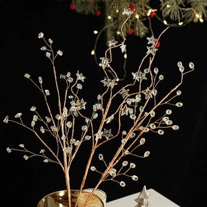Golden Christmas tree branches with crystal star ornaments in a festive vase setting