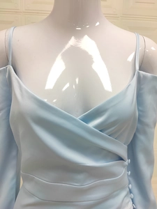 Detail of light blue off-shoulder dress with V-neck cross design and side buttons