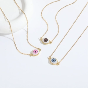 Drei feine Evil Eye Halsketten in Pink, Braun und Blau mit Goldketten auf weißem Hintergrund