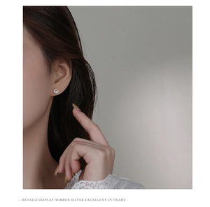 Detail showing asymmetric silver planet and moon stud earrings with zircon on a model