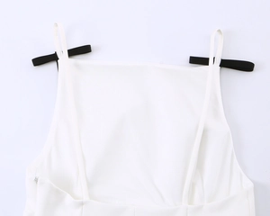 Detail van een witte hemdtop met dunne bandjes en een verborgen rits aan de zijkant