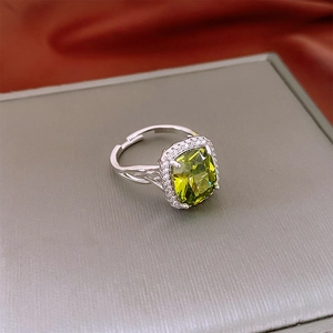Detailed close-up of a vintage emerald green cushion-cut zircon ring with silver halo band