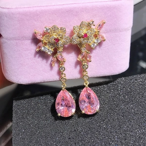 Detail of flower earrings featuring pink pear-shaped crystal drops and gold finish