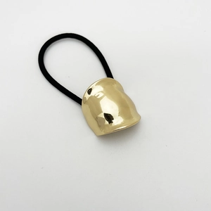 Detailed view of irregular golden alloy charm on a high-elastic black ponytail holder