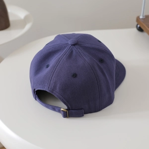 Détail de la boucle en métal réglable et du tissu en sergé bleu marine à l'arrière du chapeau