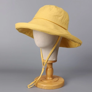 Detail of yellow cotton-linen sun hat with adjustable windproof cord on a display stand