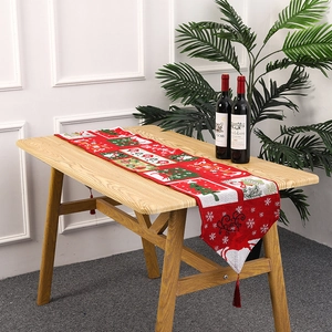 Christmas table runner with red and green pattern, festive tassels on wooden table