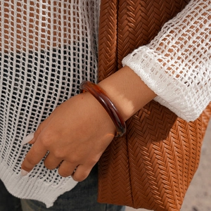 Détail d'un bracelet en acrylique ambré au poignet avec un style de tenue en tricot