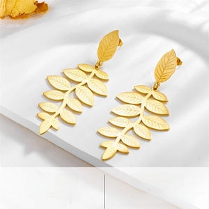 Macro shot of gold leaf earrings with intricate vein textures and metallic finish