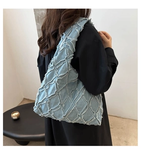 Detail showing light blue denim tote bag with quilted diamond pattern and fringe edges