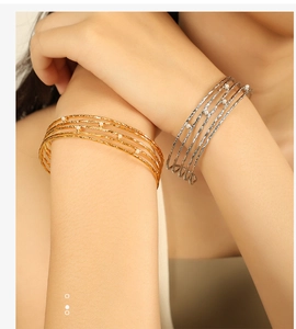 Detail of gold and silver multi-layer open bracelets with pearls and hammered metal texture