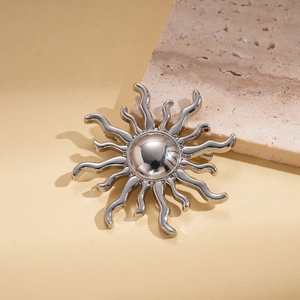 Detailed view of silver sun brooch with wavy rays and polished mirror finish surface