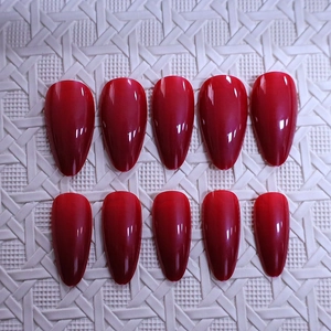 Glossy deep red almond fake nails set of 10 pieces on white textured background