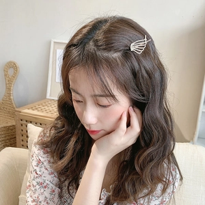 Detail of a silver wing-shaped hair clip with sparkling rhinestones on brown wavy hair