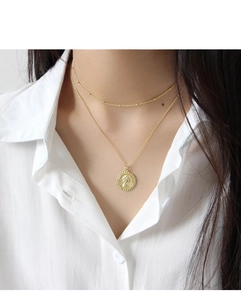 Gros plan d'un collier doré double épaisseur avec pendentif pièce sur une chemise