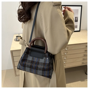 Détail du sac seau en laine à carreaux avec poignée en bois et finitions en cuir