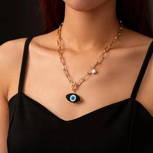 Close-up of golden chunky chain necklace featuring an Evil Eye pendant with clear crystals