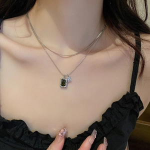 Detail of double-layer silver chain featuring an emerald green zircon pendant on neck
