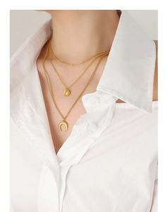 Close-up of layered gold celestial necklace with star and moon charms on model