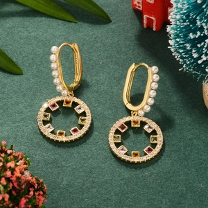 Golden round earrings with colorful zircon and white pearls on festive green background