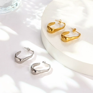 Detail showing irregular geometric C-shaped earrings in polished gold and silver finishes