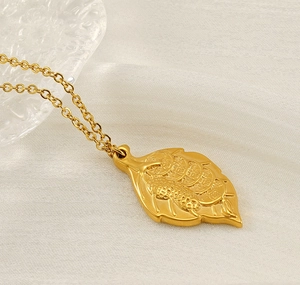 Macro shot of gold leaf pendant with leopard and coin motifs on an O-chain necklace