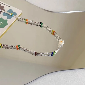 Close-up of rainbow beaded necklace featuring a white flower pendant and colorful accents