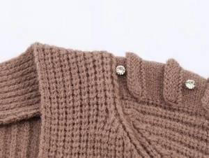 Macro view of brown knit cardigan featuring detailed texture and rhinestone shoulder buttons
