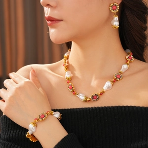 Detail of vintage necklace set with baroque pearls, red gemstones, and diamonds on model