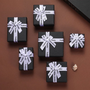 Flat lay of black textured jewelry boxes in various sizes with white fashion ribbons