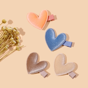 Detail of four velvet heart-shaped hair clips in orange, blue, brown and beige colors