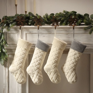 Set of four knitted Christmas stockings with diamond textures hanging on a festive fireplace