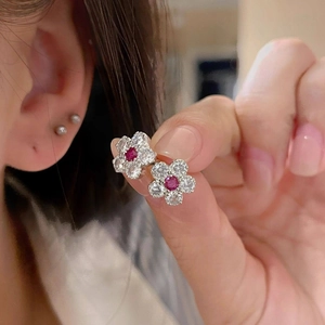 Detailed close-up of a flower stud earring with a red gemstone and white zircons